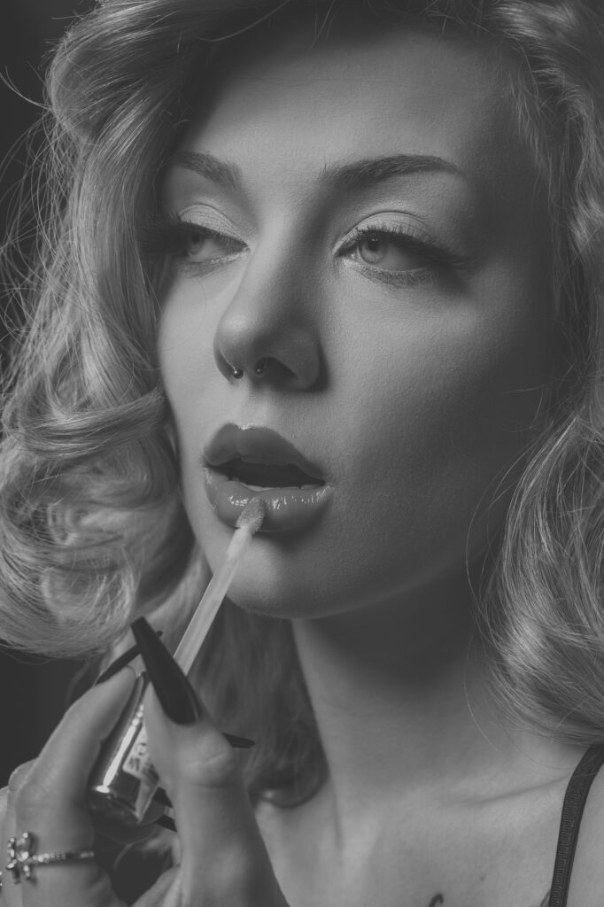 Mia trägt Lipgloss auf, Beauty-Nahaufnahme im Studio, Schwarz-Weiß