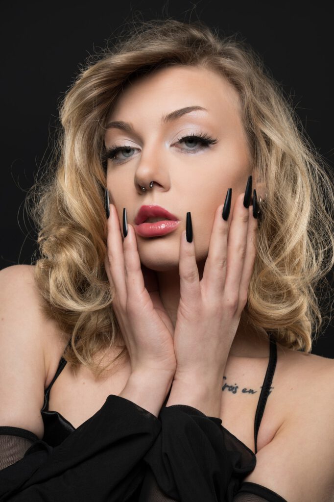 Beauty-Porträt von Mia mit Händen am Gesicht und sichtbarem Tattoo an der Schulter