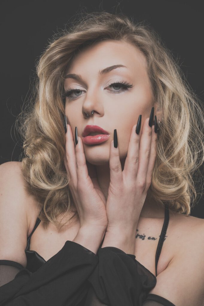 Beauty-Porträt von Mia mit Händen am Gesicht und sichtbarem Tattoo an der Schulter