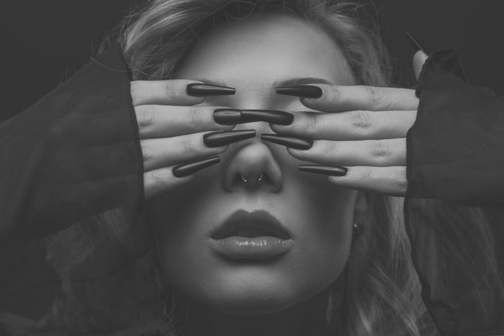 Mia verdeckt die Augen mit den Händen, Beauty-Nahaufnahme mit Krallennägeln, Schwarz-Weiß