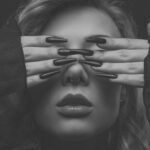 Mia verdeckt die Augen mit den Händen, Beauty-Nahaufnahme mit Krallennägeln, Schwarz-Weiß