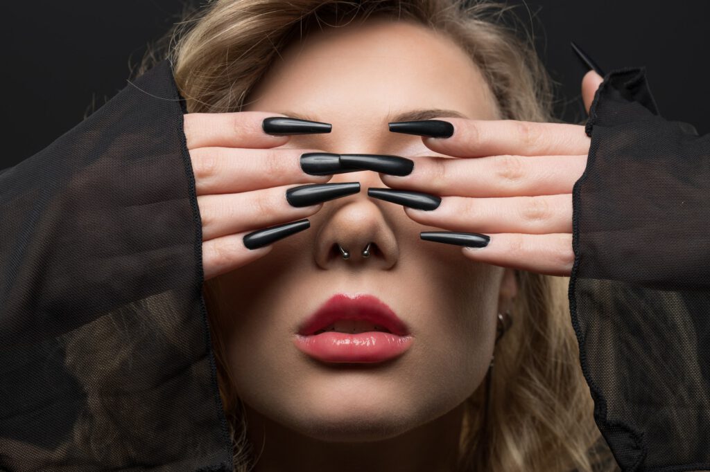 Mia verdeckt die Augen mit den Händen, Beauty-Nahaufnahme mit Krallennägeln