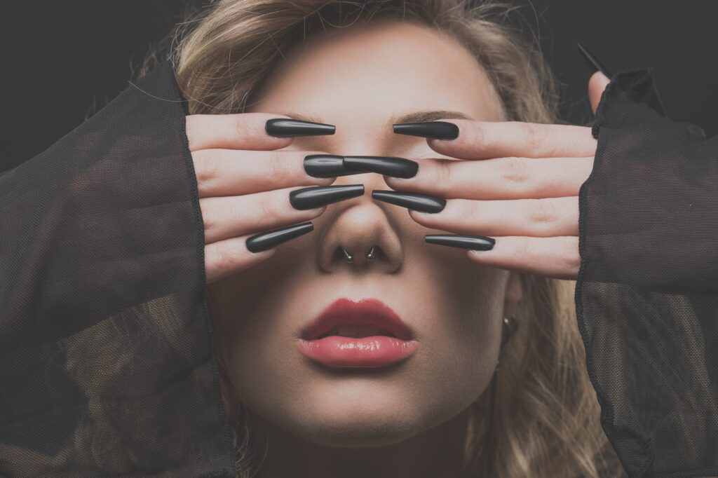 Mia verdeckt die Augen mit den Händen, Beauty-Nahaufnahme mit Krallennägeln