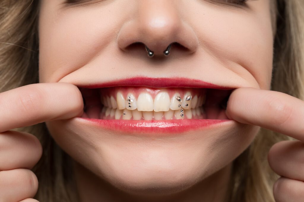 Nahaufnahme von Mias Lächeln mit Zahnschmuck und Septum-Piercing