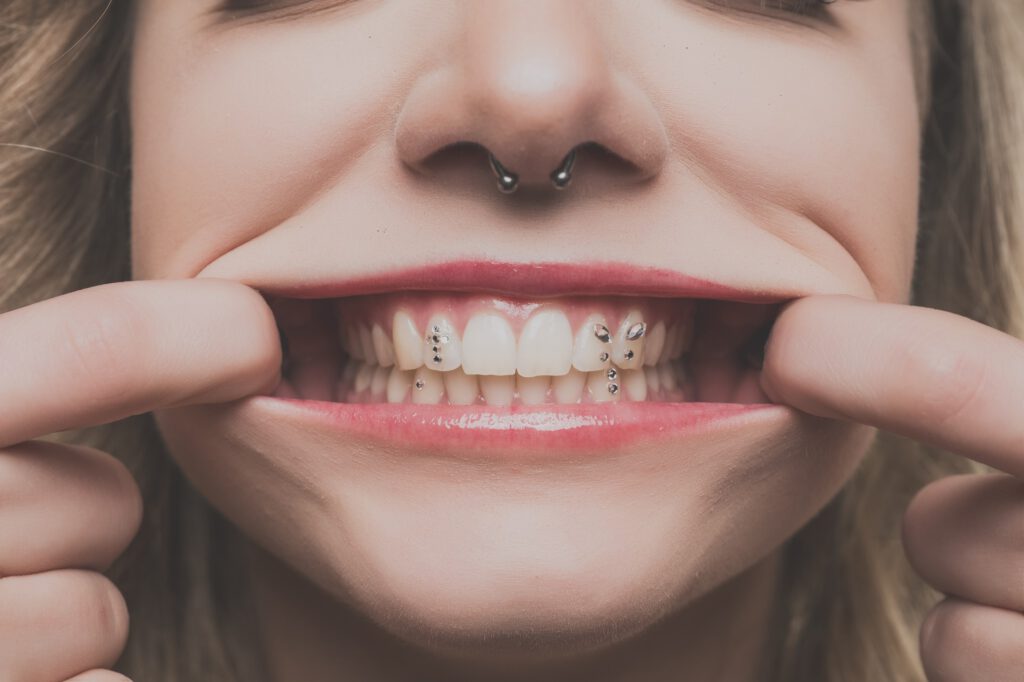 Nahaufnahme von Mias Lächeln mit Zahnschmuck und Septum-Piercing