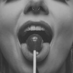 Mia mit einem Lolli im Mund, verspielte Beauty-Nahaufnahme, Schwarz-Weiß