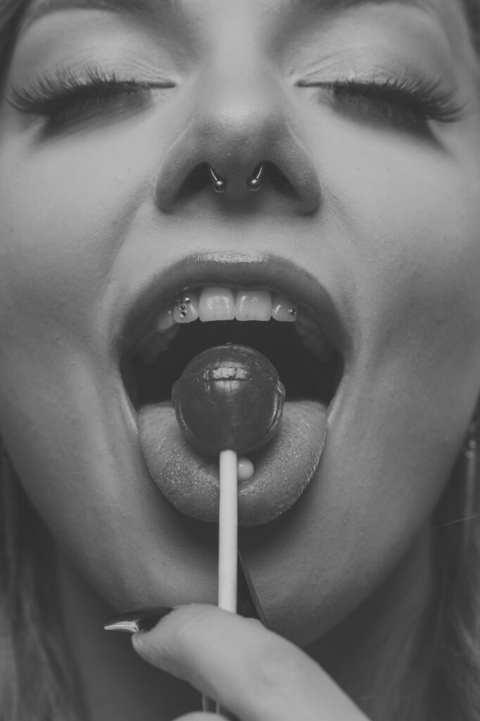 Mia mit einem Lolli im Mund, verspielte Beauty-Nahaufnahme, Schwarz-Weiß