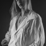 Schwarz-Weiß-Portrait von Annika im Studio: im weißen Oversize-Hemd mit Kreuzkette, Blick zur Kamera