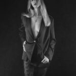 Schwarz-Weiß-Portrait von Annika im Studio: offener Blazer und gemusterte Leggings, Hand an der Hüfte