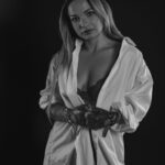 Schwarz-Weiß-Portrait von Erika im Studio: offenes weißes Hemd über Spitzentop, lange dunkle Handschuhe