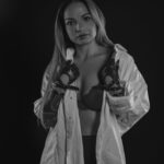 Schwarz-Weiß-Portrait von Erika im Studio: weißes Hemd und Spitzentop, Hand mit dunklem Handschuh vor der Brust