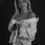 Schwarz-Weiß-Portrait von Erika im Studio: gerafftes weißes Hemd und dunkle Handschuhe, Blick zur Kamera