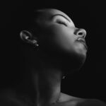 Schwarz-Weiß-Portrait von Lilly im Studio: Kopf in den Nacken gelegt, Lichtkante auf Hals und Schulter