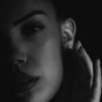 Schwarz-Weiß-Portrait von Lilly im Studio: Nahaufnahme mit Hand an der Wange, Gesicht im Streiflicht