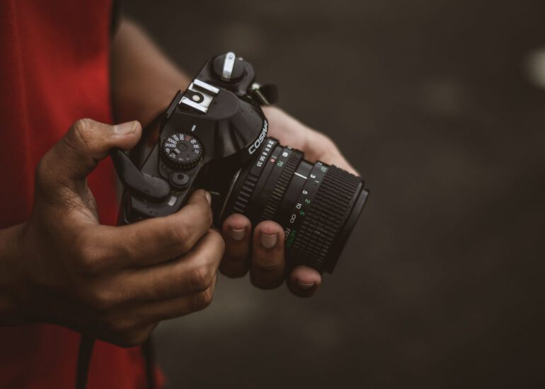 Fotograf haelt eine Kamera in der Hand